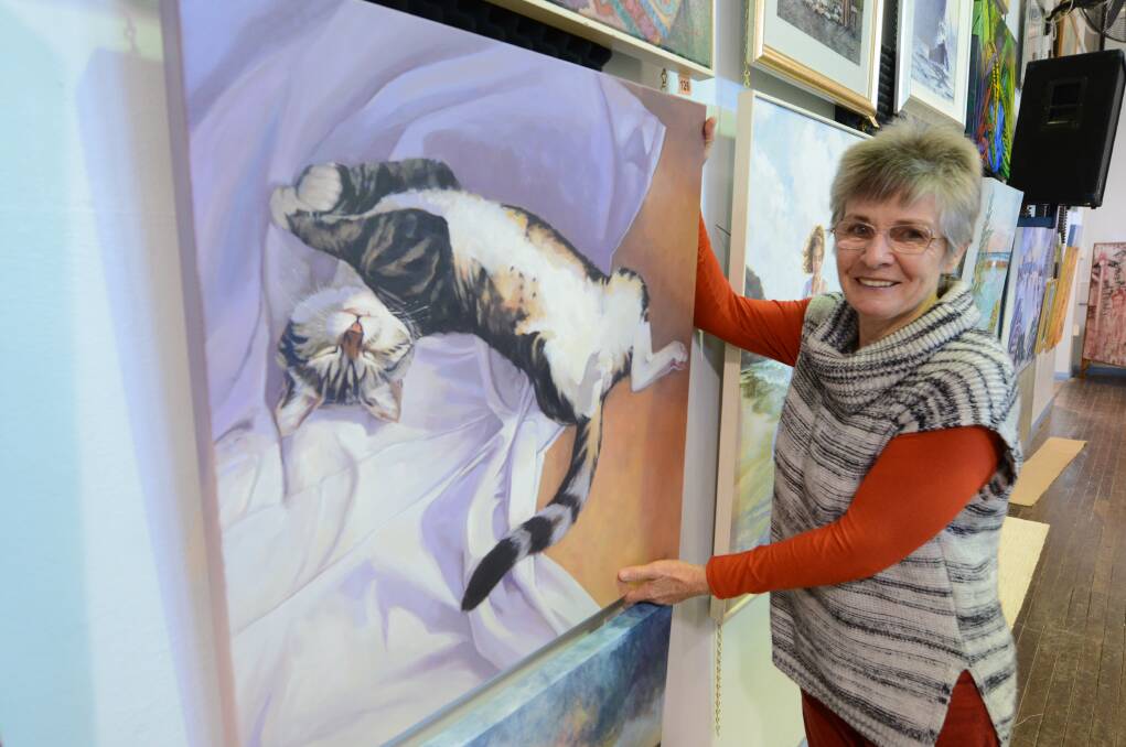 Exhibition secretary and artist Helga Visser hangs her work Purr-fect Repose. Helga said her cat often settles in on the drop sheet near her feet while she paints.