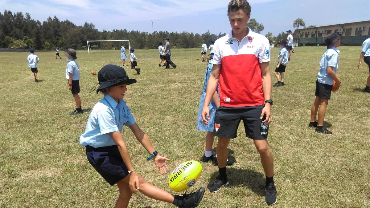 Sydney Swans player Will Hayward teaching a Taree Public School student some skills at a recent clinic.