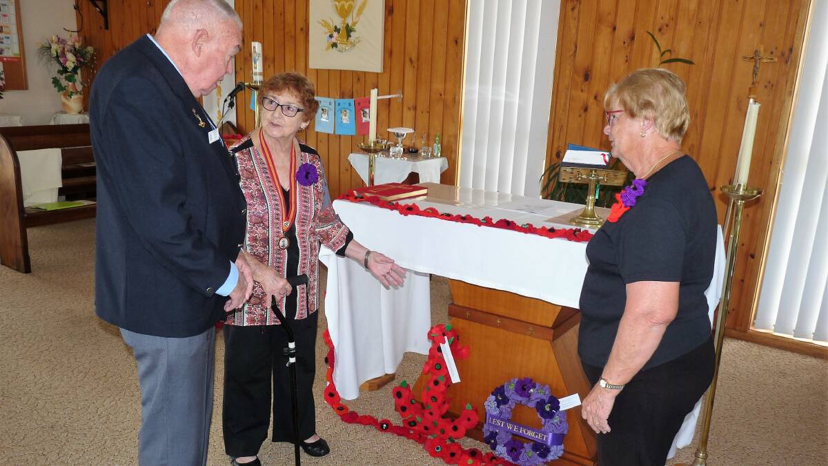Old Bar RSL Sub-branch president, Brian Carr, is provided with information about the purple poppies by Yvonne Bentley and Jenny Fisher, the coordinators of the project.