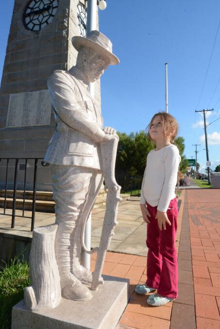 Amelia Lewis inspects the digger statues which now stand guard at Taree's Memorial Clock in Fotheringham Park, the stage for Anzac Day dawn and commemoriation services.
