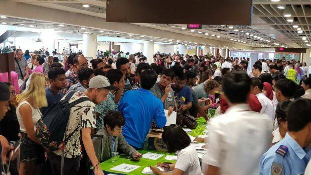 Crowds of passengers cram customer service desks set up at Denpasar airport's international terminal on Monday. Photo: Amilia Rosa
