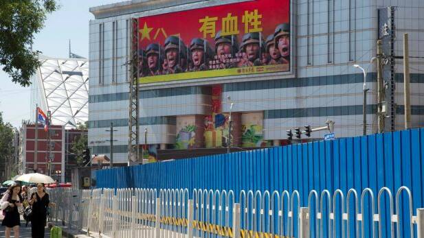 People walk near a billboard of the Chinese military reading "courageous", in Beijing, last month. Beijing is intensifying its warnings to Indian troops to get out of a contested region high in the Himalayas where China, India and Bhutan meet. Photo: AP