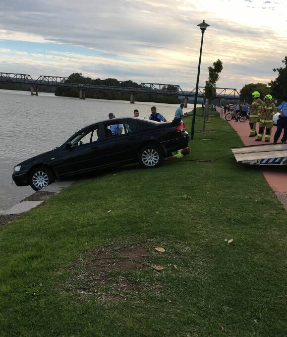 Off the road: A tow truck hauls the vehicle from where it was wedged on the banks of the Manning River on Tuesday afternoon. The driver was later charged with high range drink driving. 
