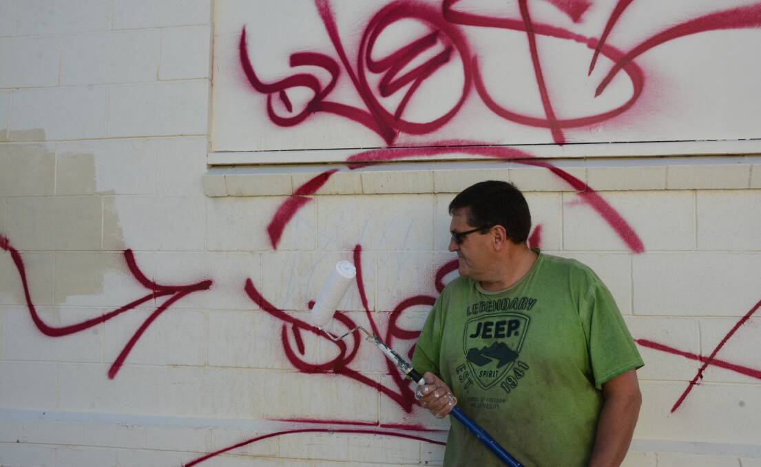 Had enough: Taree business owner Peter Bolte took to the graffiti with a paint roller. 