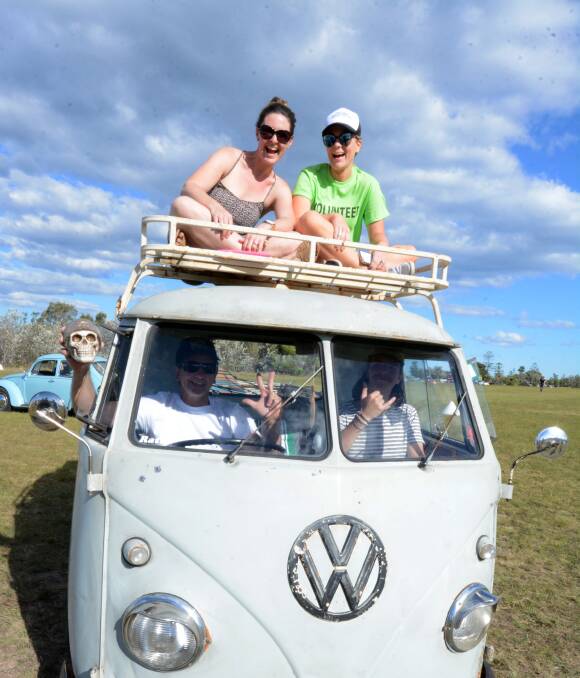 Riding high: Mhora Davies and Erin Byrne ride atop a Kombi while Bruce Jones and Dylan Gee take the wheel and ride shotgun. The Kombi was one of 249 on display at the beachside festival. Photo: Scott Calvin. 