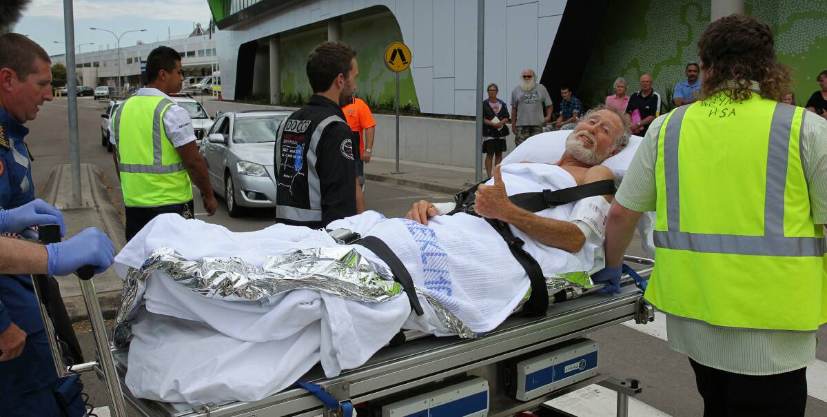 GOOD SPIRITS: Shark attack survivor Colin Rowland gives the thumbs up as he is wheeled into John Hunter Hospital for emergency surgery on lacerations to his foot and arm after being bitten while surfing. Picture: Max Mason-Hubers.