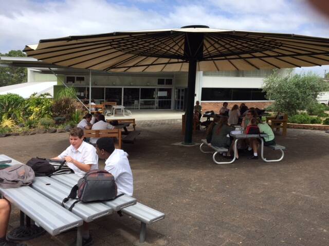 St Clare's High School students shelter shade under the large umbrella. Senior students have welcomed the shade and year seven students are pleased that there is no longer an obstruction to their handball game, according to principal Peter Nicholls.