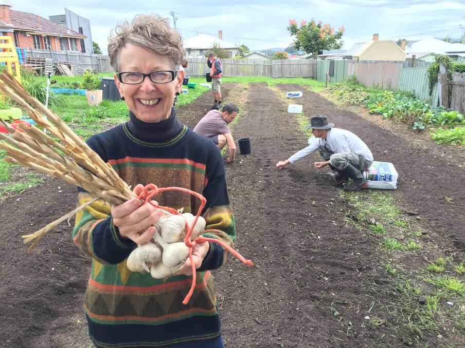 Shirley Pearson holds a bunch of garlic grown at the garden in 2016. It was soon broken down and its seed planted by volunteers in the long garden beds. Photo: Ainslee Dennis.