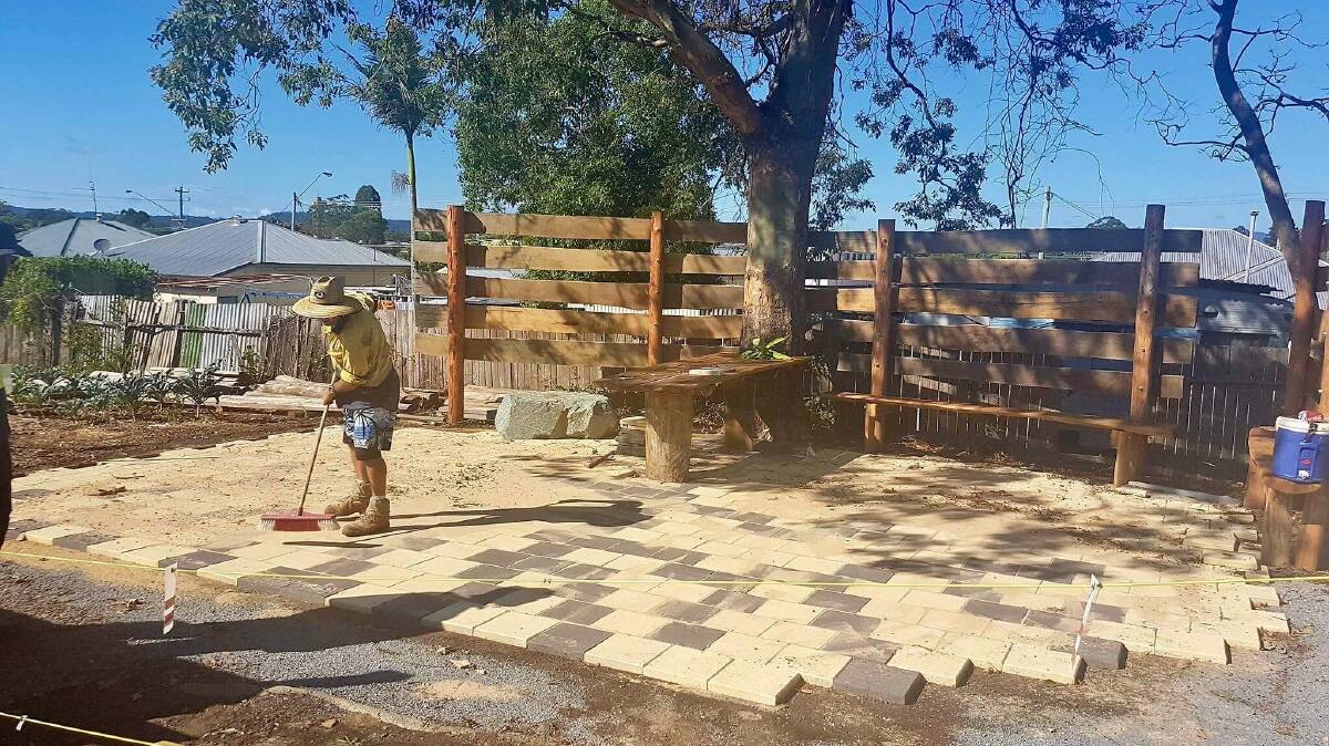Kye Baker sweeps the newly paved area at Taree Community Garden. The paving pattern is inspired by the shade of the tree branches.