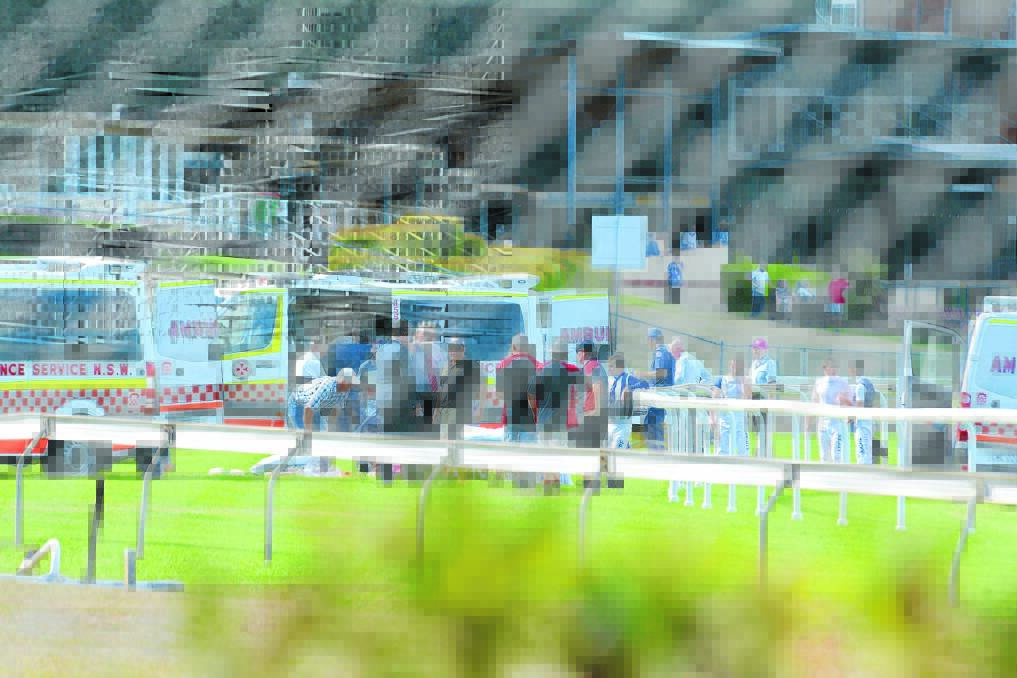 Ambulance services treat the jockeys on-track after the fall on Monday.