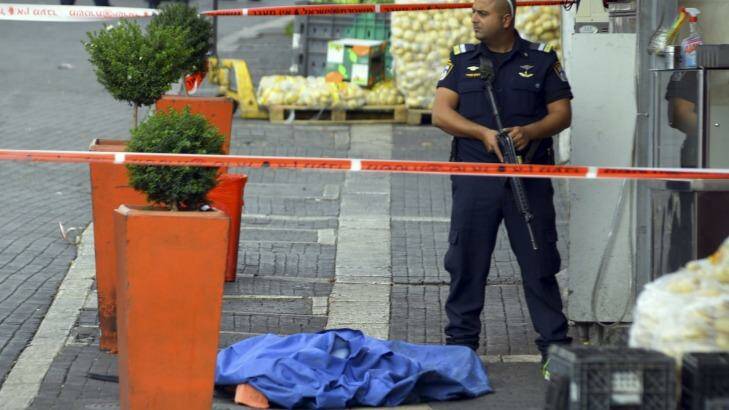 An Israeli policeman stands by the body of a Palestinian at the scene of an stabbing attack in Jerusalem. Photo: Mahmoud Illean