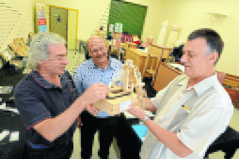 Wingham High School design and technology teacher Graeme Taylor, Taree Manning River Men's Shed member Terrey Boys and Colin Husband, design and technology teacher at Taree High School, with the hydraulic arm, which was made by Taree High School student Jakeb Chester.