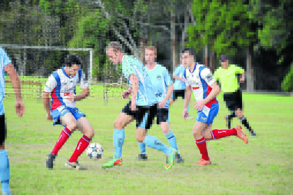 Sam Mitchell from Taree confronts Old Bar s Grant Suters during the Football Mid North Coast Premier League clash at Omaru Park. Taree won 3-2.