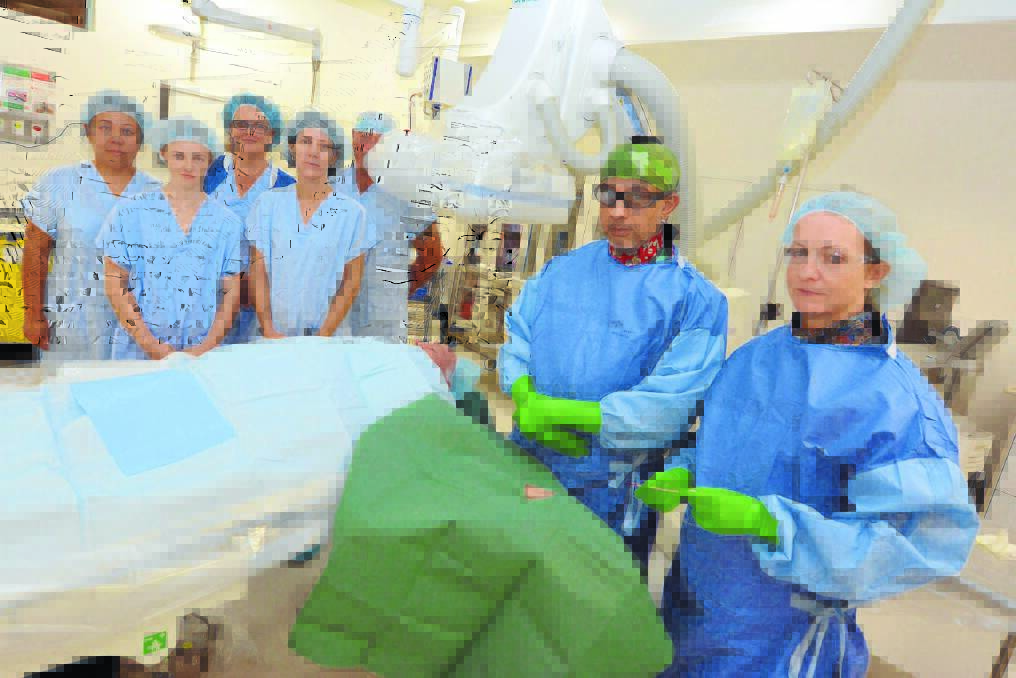 Cause to swear: Cardiologist Dr Sesh Narasimhan stands ready to do a cardiac procedure in the Mayo Private Hospital Cardiac Catheter Laboratory. Dr Narasimhan and his team Linda Pearce, Cindy Bradshaw, Alyce Inman, Max Minnett, Toni Vause and scrub nurse (right) Rhian Lewis seek public patient access to the private hospital s cath lab facilities.