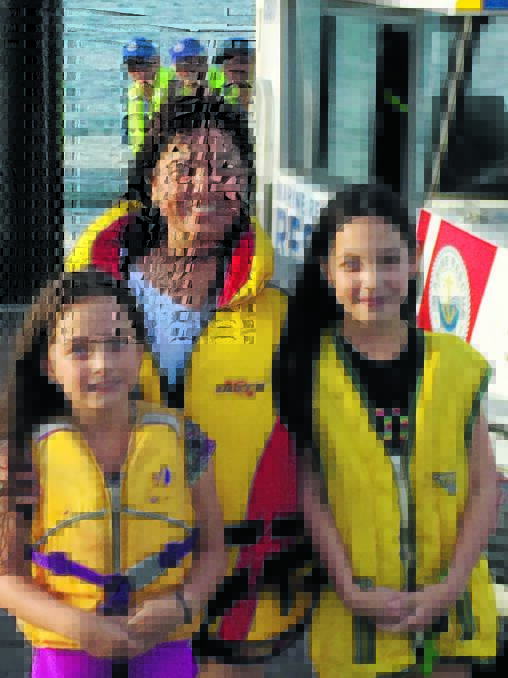 Samantha Lawson, Eva Arambala and Tia Lawson, safely back on shore after their Hobie Cat capsized, with rescue crew members Kevin Bailey, John Peers and Aaron Orton (background).