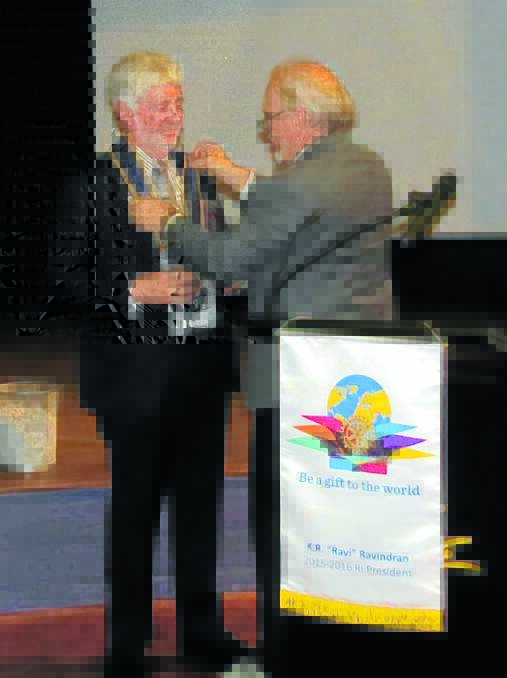 Taree solicitor Maurie Stack receives the chains of office from Greg Moran, the outgoing district governor. 