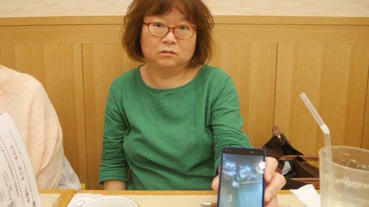 Yoshiko Furukawa uses her mobile phone to show photos of the damage the 2011 Tohoku earthquake inflicted on her house in Fukushima. Photo: Philip Wen