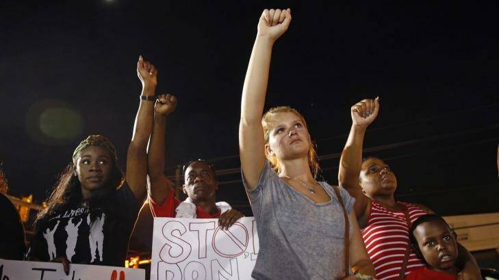 Mourners in Baton Rouge raise their fists during a night rally on Monday in honour of Alton Sterling, who was shot and killed by Baton Rouge police while selling CDs outside the convenience store. Photo: Gerald Herbert/AP