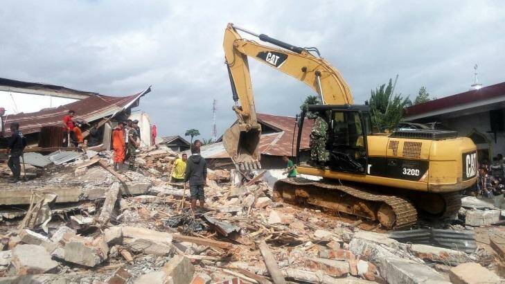 Heavy equipment cleans up a site of a petrol station coffee shop where 10 people were thought to be trapped in Pidie Jaya regency, Aceh. Photo: Twitter/@IloveAceh