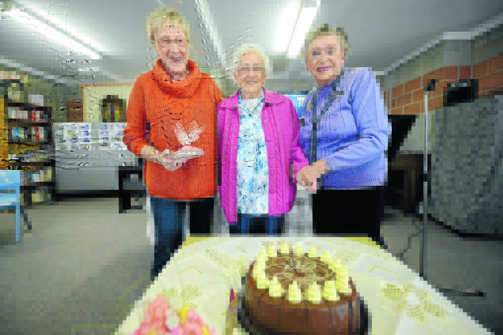 Robyn Osborn and Margaret McDonald stand on either side of cake cutter Doris Tickle.