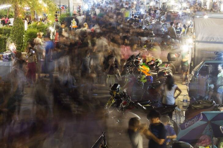 Shoppers walk past stalls at the Jatujak Green night market, known as the JJ Green night market, in this long exposure photograph taken in Bangkok, Thailand, on Saturday, July 30, 2016. Thailand is scheduled to release Consumer Price Index (CPI) figures on Aug. 1. Photographer: Brent Lewin/Bloomberg