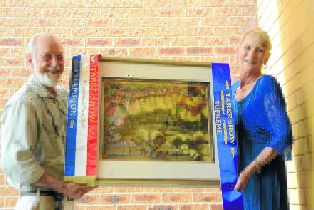 A champion collaboration: Dr Jim Frazier OAM ACS and Lynne Jones hold the paper tole artwork, "Dancing for the Earth". For 12 months Lynne worked to recreate Jim's artwork "Another Place, Another Time" using the art of paper tole. She entered it in Taree Show where it came away with an array of awards. The artwork will be on show this weekend at Artisans Retreat, as part of the Akoostik Festival. Photo by Lauren Green.