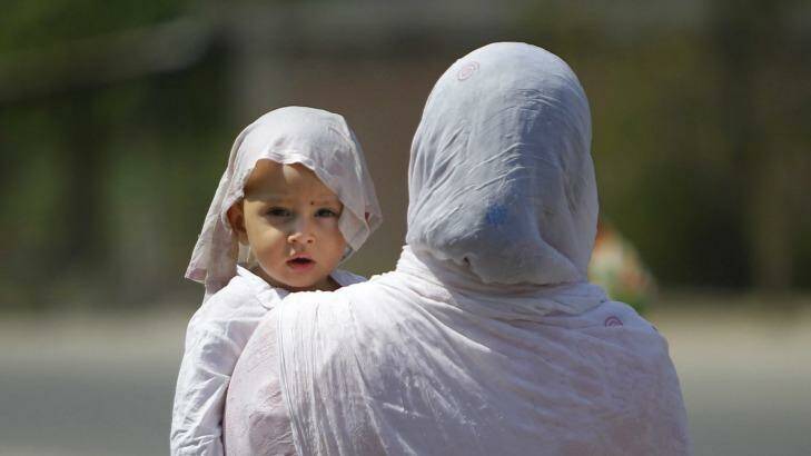 A mother and a child with his head covered with a wet towel to protect them from the scorching heatwave last week in India that set a record temperature in India of 51 degrees. Photo: Channi Anand