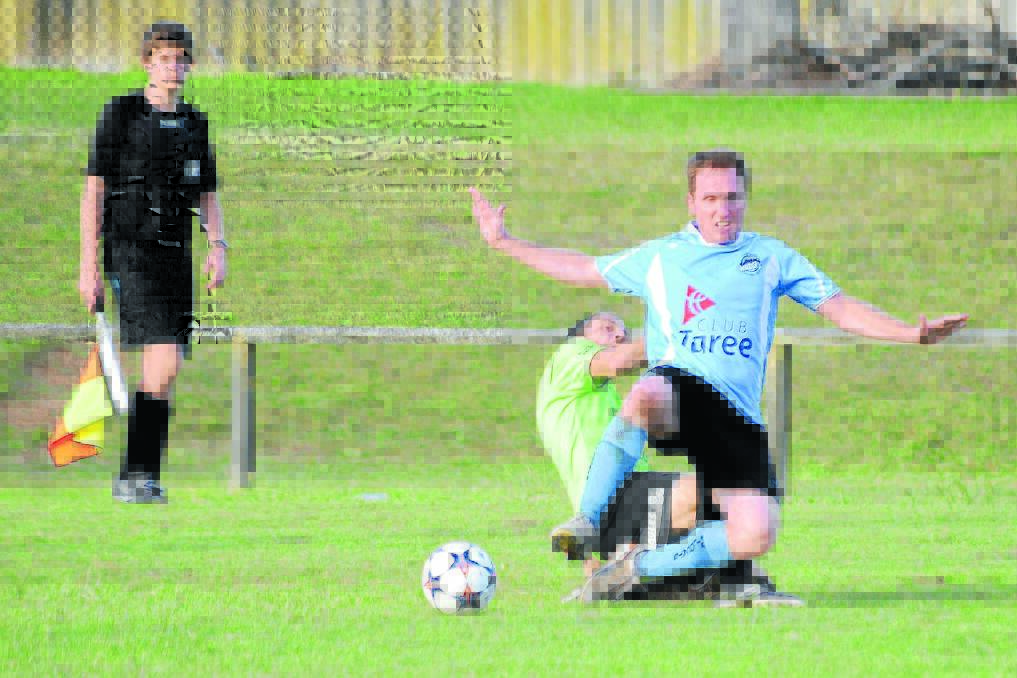 Justin Atkins from Taree battles for possession during a Football Mid North Coast Premier League clash last season, watched by a sideline official. 