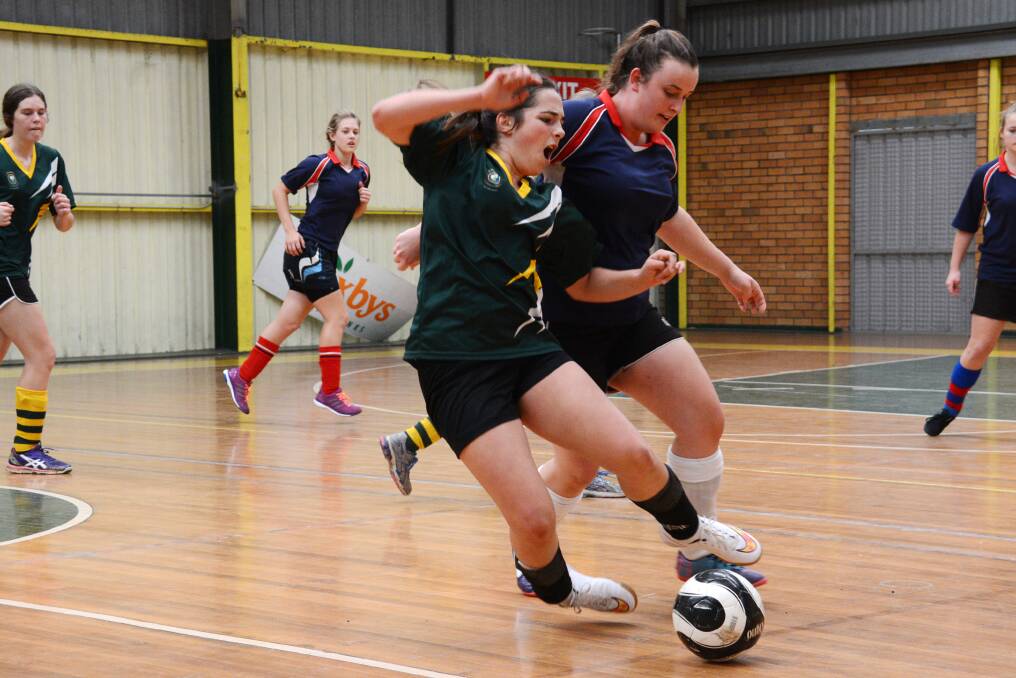 Rosie White and Thea Wespi clash during the St Clare's/Wingham High match in the girls tournament played as part of the regional futsal championships this week at Saxby s Stadium. More photos www.manningrivertimes.com.au