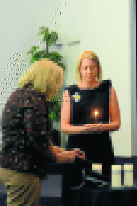 Judy Mulheron lights a candle in remembrance of her son, Glenn McEnallay. She is assisted by Alexandra Reid.