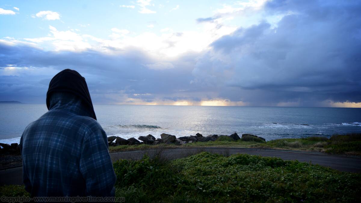 A fisherman looks out to the storm clouds rolling in at Crowdy Head, earlier this morning. 