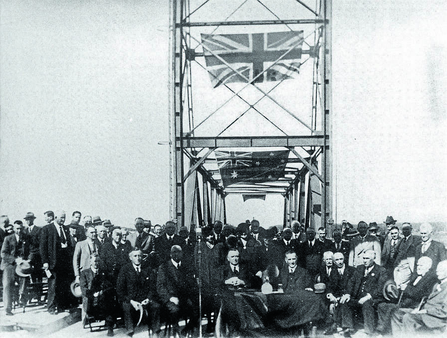 The official party and general public at the opening of the Martin Bridge across the Manning River. Seated at the table on the left is Herb Milligan, Manning Shire Council president, L.O. Martin MP (after whom the bridge was named) centre, and third from the right of the photo is W P Chapman, mayor of Taree. This photo can be found in "Past Days Around the Manning" compiled by John Doust. 
