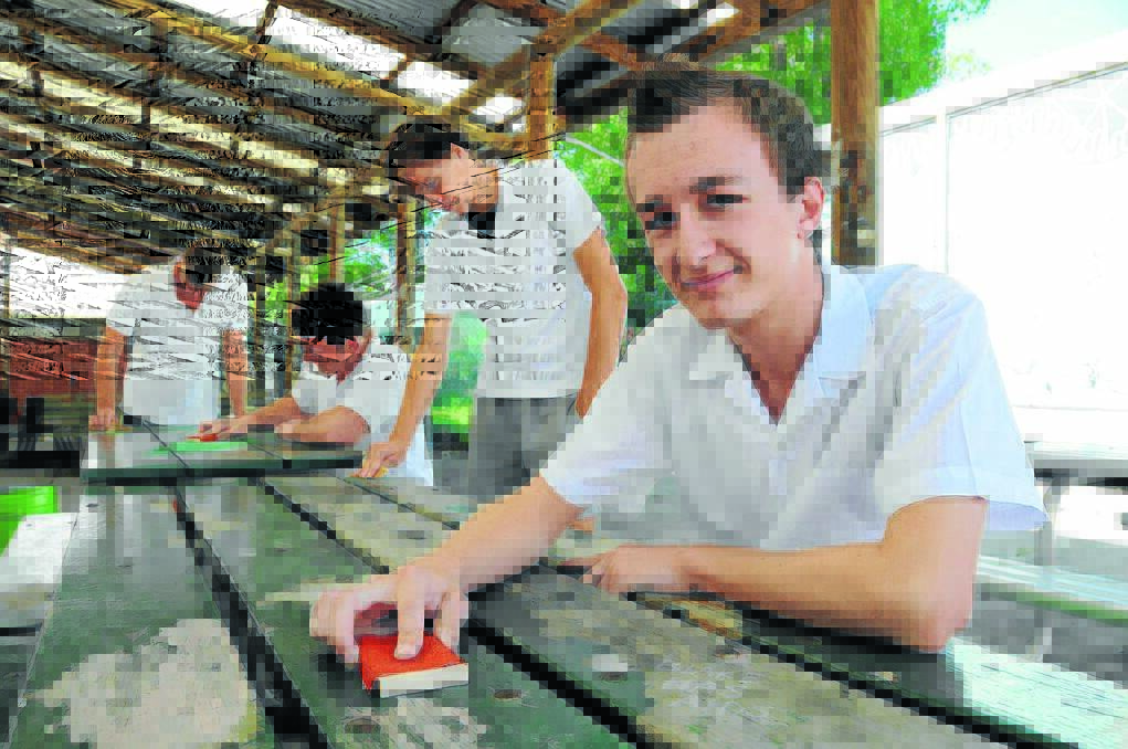 Blocks of sandpaper and a bit of elbow grease from Taree High School students (from left) Dalen Hilton, Jaden Streeting, Cody Hodges and Adam Alchin, work off old paint from the outdoor school tables.