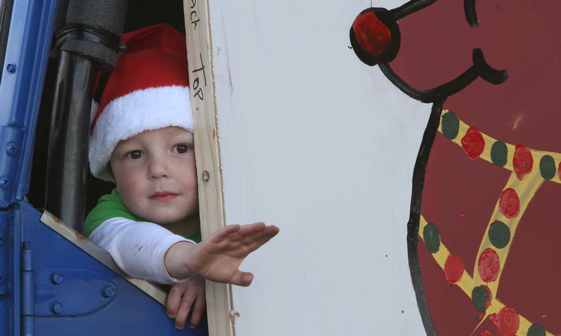 TASMANIA: William Eiszele, 2, squeezes through a little gap to wave to the crowd in the Penguin Leo Clubs float at the Penguin Christmas Parade.