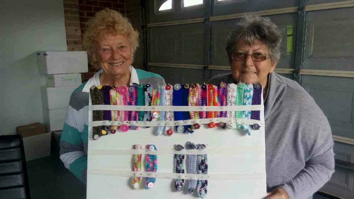 Joan and Margaret pictured with their knitted ear savers that they have donated to local businesses, hopspitals and members of the community. 