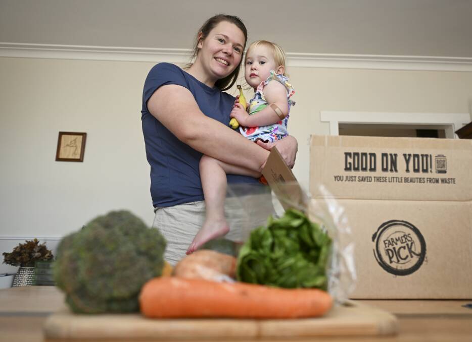 Jackie Walker, pictured with her two-year-old daughter Violet, has been subscribing to Farmers' Pick for a seasonal produce box for more than a year to help curb rising living costs. Picture by Lachlan Bence