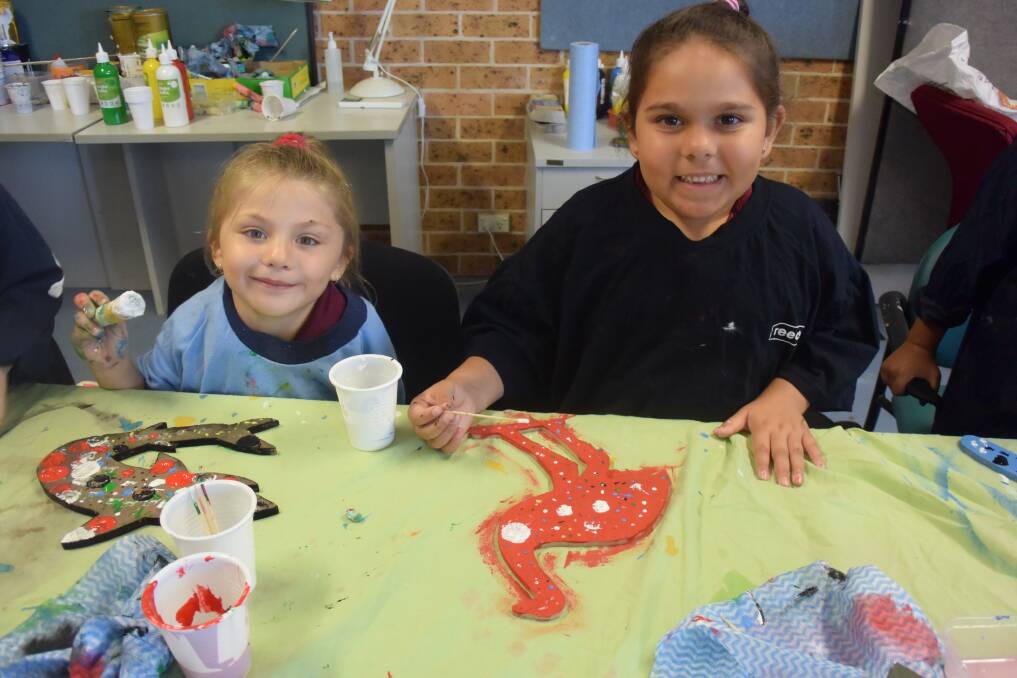Marlee Simmonds and Tailei Clarke using sticks and chalk to create their artworks.