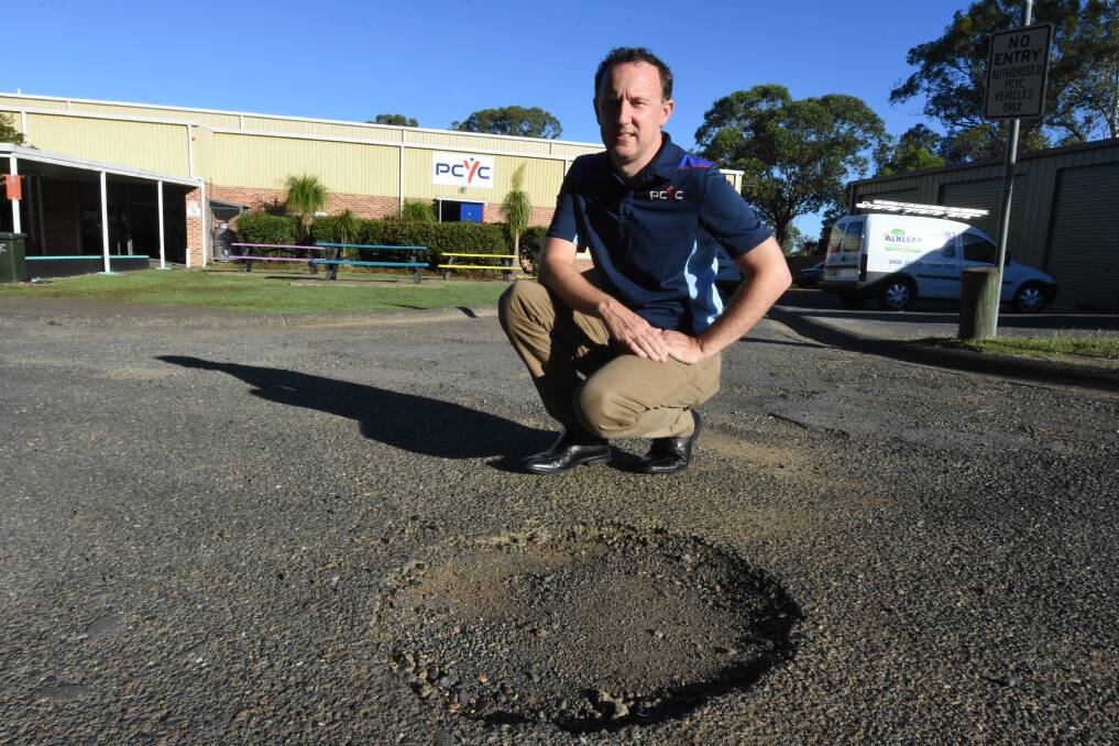 Taree PCYC manger Justin Hayes with one of the hundreds of potholes in the road leading to the club.