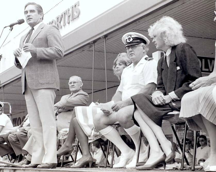 Greater Taree City mayor Les Brown speaking at the opening of the Manning Aquatic Festival in 1985. Ted Hill, the MC for the Aquatic parade, is seated between Liz Hayes and Wendy Machin.