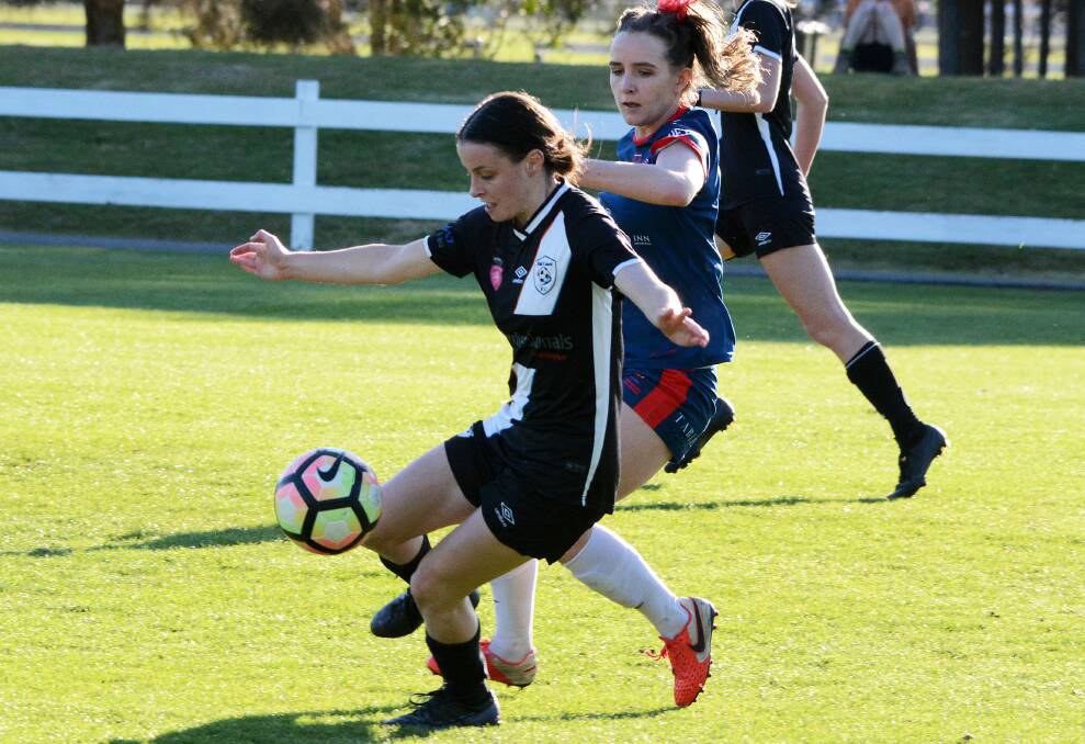 Mid Coast's Natasha Ruge tries to control the ball despite attention from a Merewether defender during the clash at Taree on Saturday. Mid Coast won 3-2.