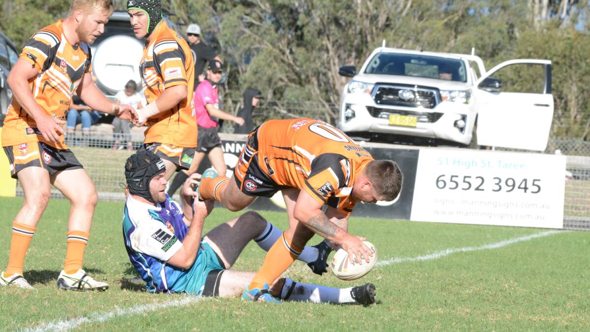 Taree City captain-coach Todd Bridge stops Wingham Nick Beacham during the first half of the clash at Wingham.