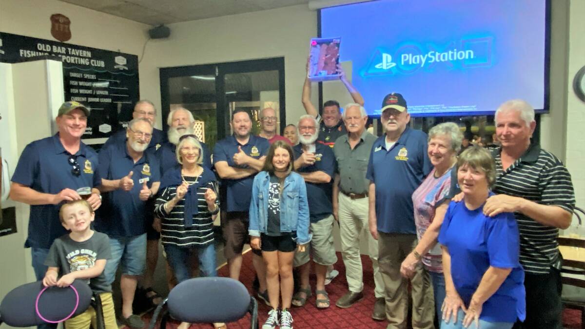 Old Bar RSL Sub-branch members and their family briefly came together for this photo with a winner in the background. See story below.