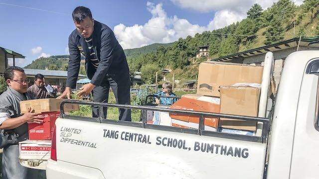 Yeshey, the Tang school driver, packing the ute with books.