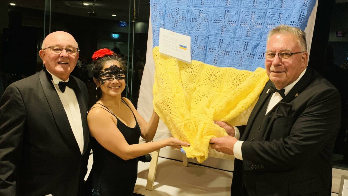 Masquerade ball host Bruce Moy and Taree Rotary president Grace Maano presenting Laurie Easter with the Ukrainian blanket.