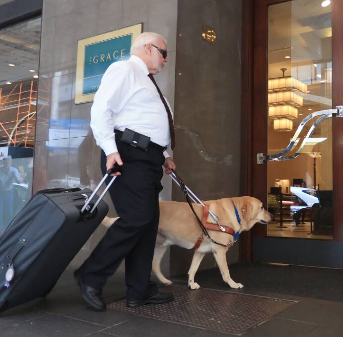 A Guide Dog handler with Guide Dog entering a hotel
