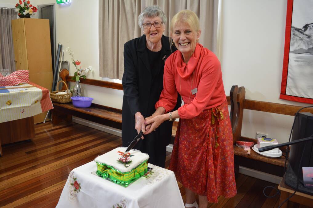 Betty Freeman cutting the Christmas cake with zone councillor, Christine Manger. 