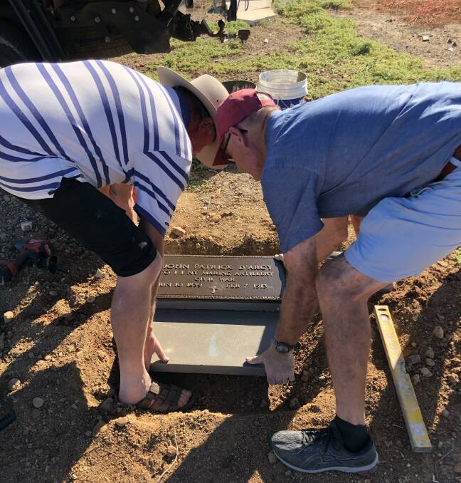 D'Arcy family members David and John place the plaque as a new headstone for their great, great uncle John Patrick. 