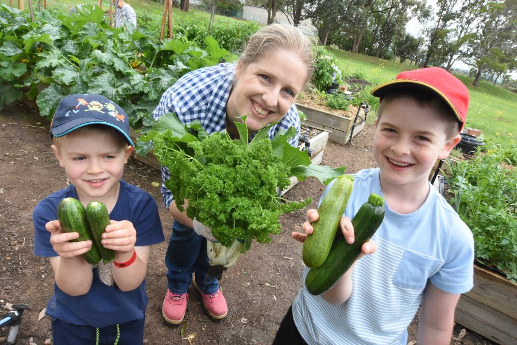 Taree Community Garden co-ordinator Bree Katsamangos with her sons, Archer and Will with their harvest of fresh produce.
