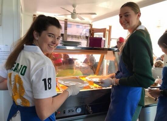 St Clare's year 10 students Clare Chapman and Jessica Horsburgh work to serve free meals at Taree Community Kitchen.