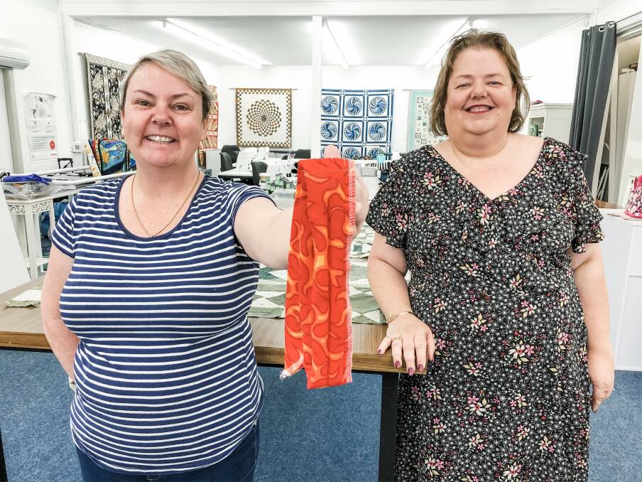 Country Pickin's at the Corner owner Robyen Gibney and Robyn Laurenson with one of the 532 cool ties made for local firies to wear around their necks. Photo: Ainslee Dennis.